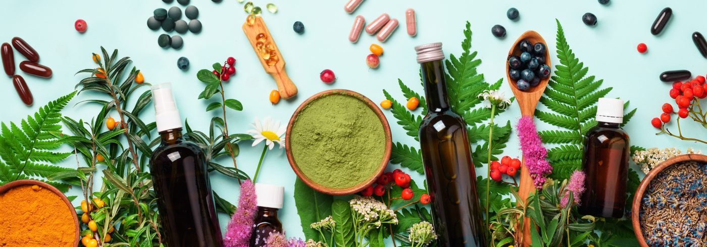 Alternative medicine. Holistic approach. Healing herbs and flowers over blue background. Top view, copy space, flat lay. Banner